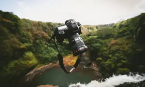 Un appareil photo bridge ou reflex flotte au-dessus d'une cascade luxuriante, prêt à capturer la beauté sauvage.