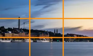 Pour comment prendre une belle photo, utilisez la règle des tiers pour cadrer ce paysage urbain au crépuscule avec des bateaux sur l'eau.