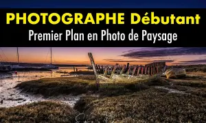 Épave de bateau en premier plan sur une plage au coucher du soleil. Au loin, des voiliers et un pont.
