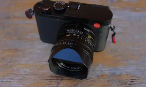 Leica Q3 test : un appareil photo noir élégant avec un objectif Summilux sur fond de bois.