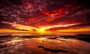 Coucher de soleil spectaculaire avec des nuages rougeoyants. Quel filtre ND pour coucher de soleil aurait pu capturer cette intensité ? La mer reflète les couleurs flamboyantes.