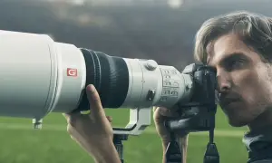 Photographe sportif utilisant un appareil photo Sony a9 II avec un téléobjectif blanc, prêt à capturer l'action sur le terrain.