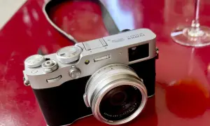 Appareil photo argenté Fujifilm X100VI sur fond rouge vif, prêt pour un test.
