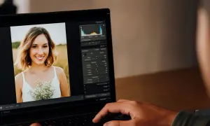 Un portrait de femme souriante est retouché sur un ordinateur portable. Lightroom sert à améliorer la luminosité, les couleurs et les détails pour un rendu parfait.