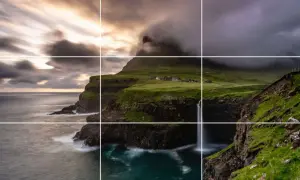 Paysage spectaculaire avec des falaises verdoyantes, une cascade tombant dans l'océan et un village pittoresque. La perspective accentue la beauté sauvage de ce lieu.