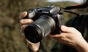 Mains tenant un appareil photo Canon EOS R7 avec un objectif. Prêt à capturer la beauté de la nature.