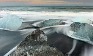 Glace sur sable noir, l'eau file en rubans soyeux grâce à la pose longue. Des diamants de glace flottent sur la plage islandaise.