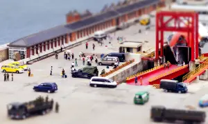 Scène de port avec des véhicules et des personnes, effet tilt shift donnant une impression de maquette.