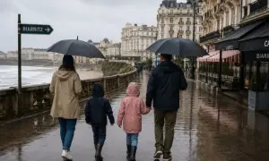 Une famille se promène sous la pluie à Biarritz, profitant de belles photos malgré le temps gris.