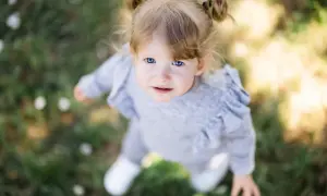 Un bébé aux yeux bleus vifs, coiffé de couettes, regarde vers le ciel. Le flouter arrière plan photo met en valeur son visage innocent.