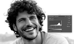 Portrait en noir et blanc d'un homme souriant, ajustant les niveaux dans Photoshop pour un rendu parfait.
