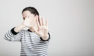 Une femme en pull rayé lève les mains pour se protéger, comme dans un exemple de copyright photo.