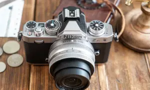 Un appareil photo Nikon Zfc argenté et noir, prêt pour un avis. Des pièces et des billets sont à côté.