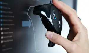 Main d'une personne tenant un appareil Spyder4 pour calibrer ecran pc. L'écran affiche un menu de calibration.