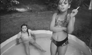 Deux jeunes filles dans une piscine gonflable, l'une fumant une cigarette, dans le style de Mary Ellen Mark.