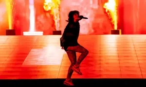 Une artiste chante sur scène, entourée de flammes spectaculaires. Cette photo de concert capture l'énergie d'un spectacle enflammé.