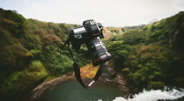 Un appareil photo bridge ou reflex flotte au-dessus d'une cascade luxuriante, prêt à capturer la beauté sauvage.