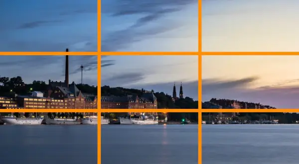 Pour comment prendre une belle photo, utilisez la règle des tiers pour cadrer ce paysage urbain au crépuscule avec des bateaux sur l'eau.