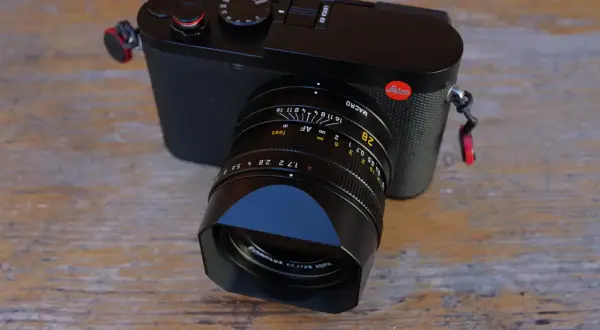 Leica Q3 test : un appareil photo noir élégant avec un objectif Summilux sur fond de bois.