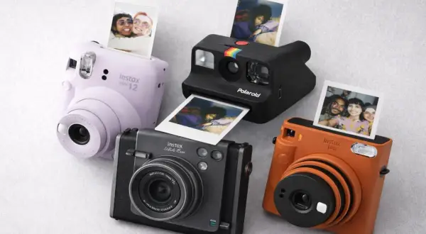 Quatre appareils photo instantanés, dont un Instax Mini 12 lilas, un Polaroid noir et un Instax orange, sortent des photos de souvenirs.
