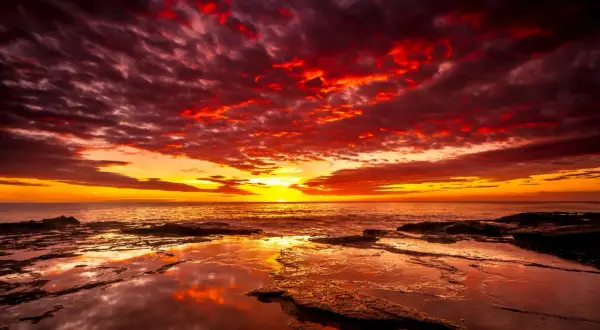 Coucher de soleil spectaculaire avec des nuages rougeoyants. Quel filtre ND pour coucher de soleil aurait pu capturer cette intensité ? La mer reflète les couleurs flamboyantes.