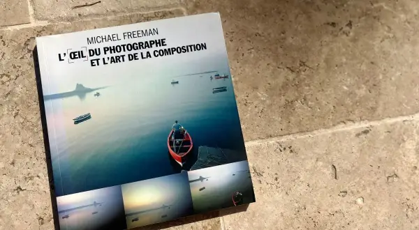 L'œil du photographe et l'art de la composition, un livre de Michael Freeman, présente des paysages marins paisibles avec des bateaux et un îlot lointain.