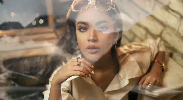 Jeune femme au regard intense, lunettes sur la tête, avec un effet vitre photoshop créant une atmosphère rêveuse.