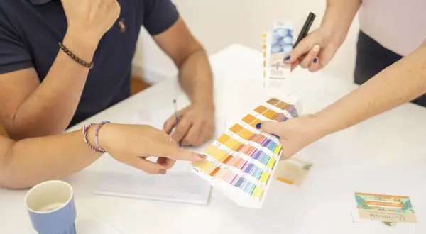 Des mains choisissent des couleurs sur un nuancier Pantone, lors d'une réunion de photo entreprises.