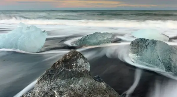 Glace sur sable noir, l'eau file en rubans soyeux grâce à la pose longue. Des diamants de glace flottent sur la plage islandaise.