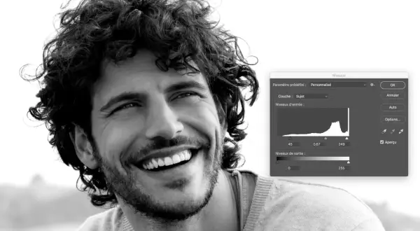 Portrait en noir et blanc d'un homme souriant, ajustant les niveaux dans Photoshop pour un rendu parfait.