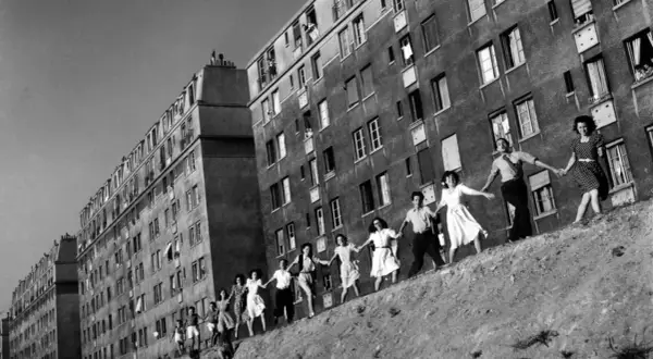 Une chaîne de jeunes gens se tient la main devant des immeubles, une scène de joie capturée dans cette photo célèbre.