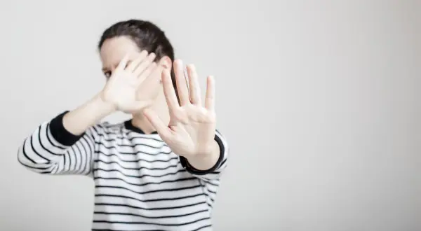 Une femme en pull rayé lève les mains pour se protéger, comme dans un exemple de copyright photo.