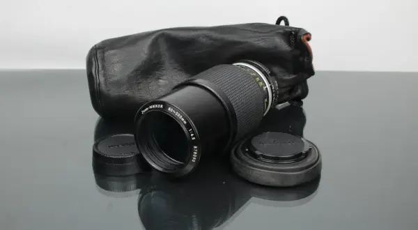 Objectif Zoom-NIKKOR 80-200mm f/4.5 avec son étui en cuir noir, prêt pour une nouvelle aventure photographique. Un classique Nikon.