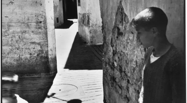 Un jeune garçon se tient dans une ruelle étroite, une ombre projetée sur le sol. Une scène typique des henri cartier bresson photos célèbres.