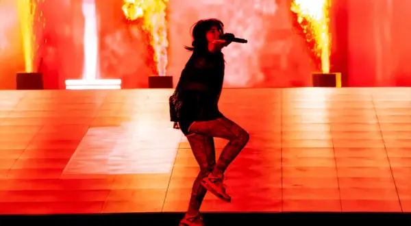 Une artiste chante sur scène, entourée de flammes spectaculaires. Cette photo de concert capture l'énergie d'un spectacle enflammé.