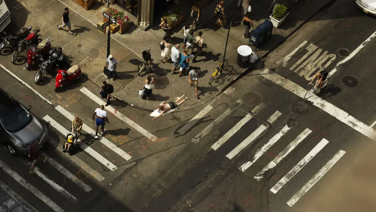 Un homme sur une planche de surf traverse une rue animée, une scène capturée par Romain Laurent.