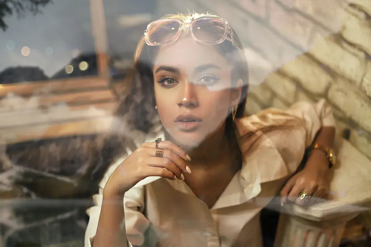 Jeune femme au regard intense, lunettes sur la tête, avec un effet vitre photoshop créant une atmosphère rêveuse.