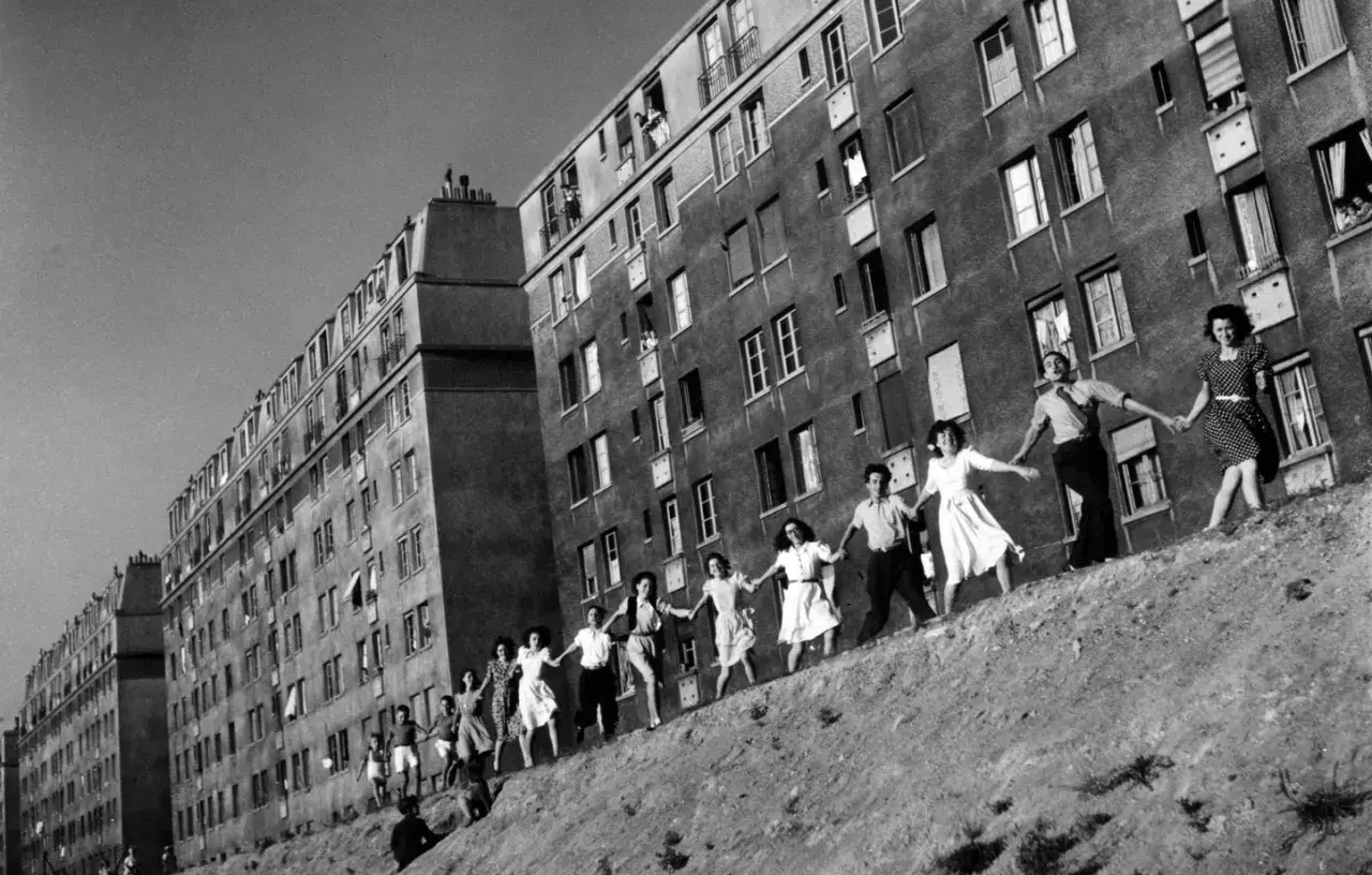Une chaîne de jeunes gens se tient la main devant des immeubles, une scène de joie capturée dans cette photo célèbre.