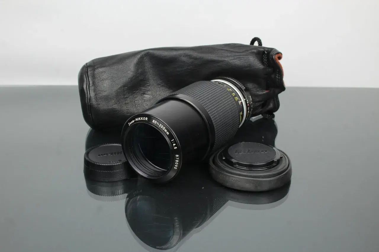 Objectif Zoom-NIKKOR 80-200mm f/4.5 avec son étui en cuir noir, prêt pour une nouvelle aventure photographique. Un classique Nikon.