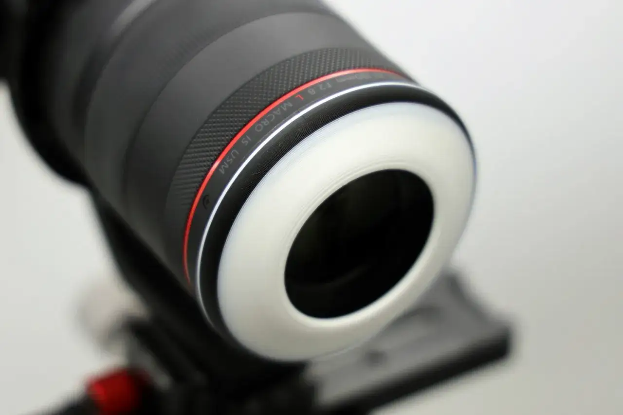 Gros plan d'un objectif macro 100mm f/2.8 L IS USM avec un diffuseur blanc. Ce photo d&eacute;tail r&eacute;v&egrave;le la texture de l'objectif.
