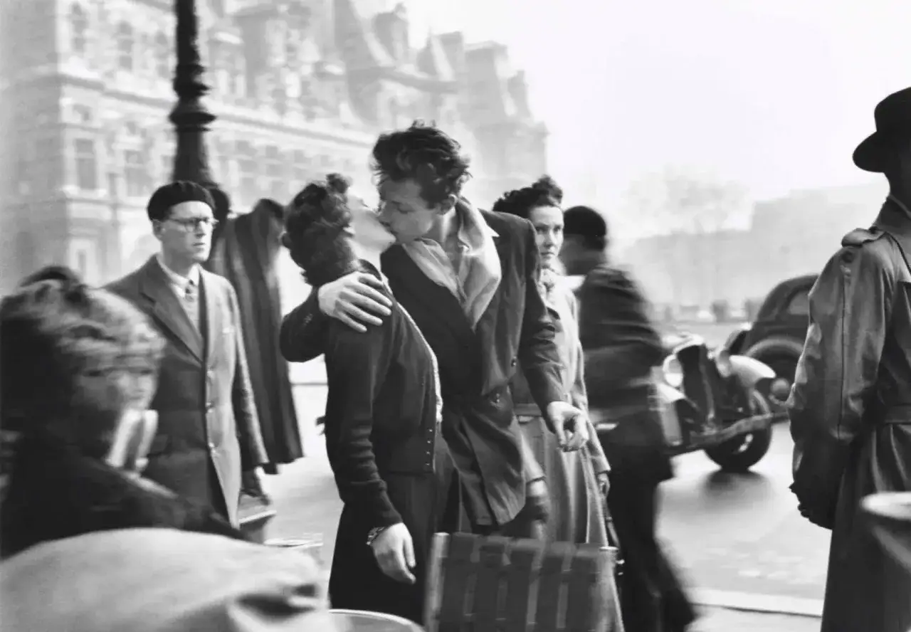 Un couple s'embrasse passionnément dans une rue parisienne, une scène de la vie quotidienne immortalisée dans cette photo célèbre.