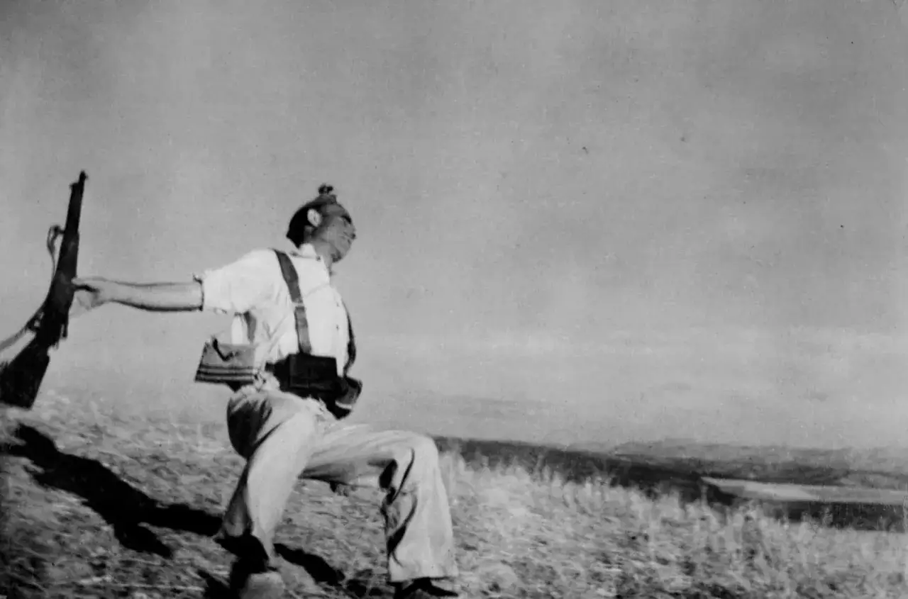 Soldat en mouvement, fusil &agrave; la main, sur une colline. Une photo historique choquante qui capture un instant de conflit.