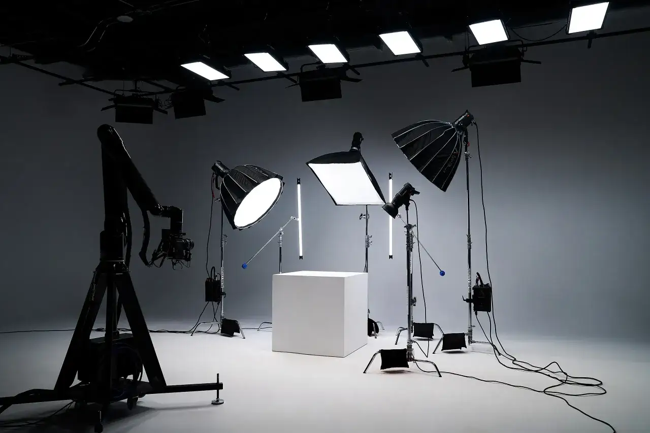 Studio prêt pour un packshot produits : cube blanc, éclairages variés, bras robotisé et caméra.