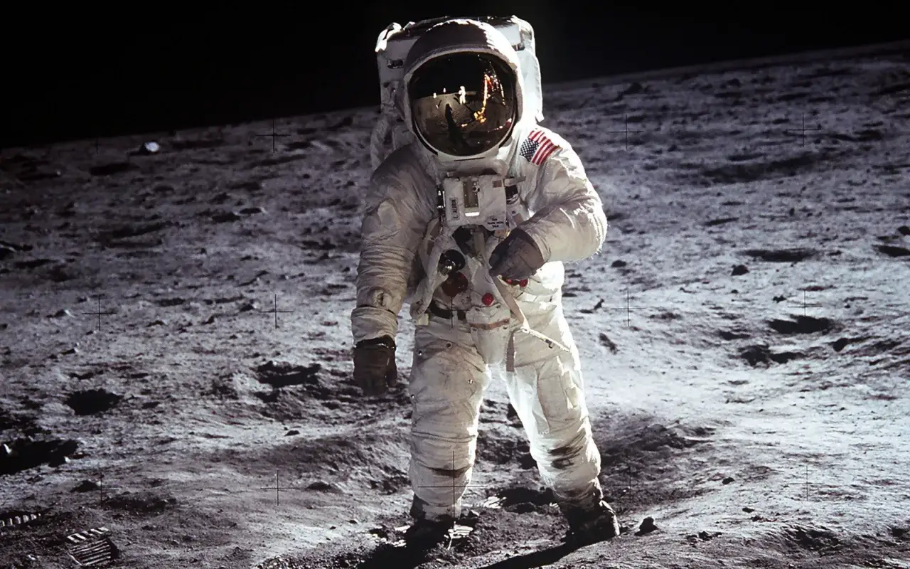 Un astronaute en combinaison spatiale se tient sur la Lune, une photo légendaire. Le drapeau américain est visible sur son épaule.