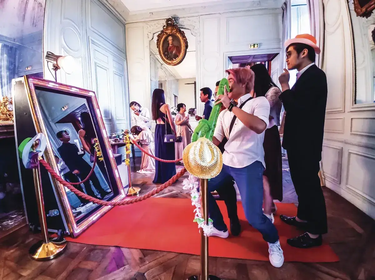 Des invités s'amusent devant un photobooth interactif, avec des ballons gonflables et des chapeaux pour des souvenirs mémorables.