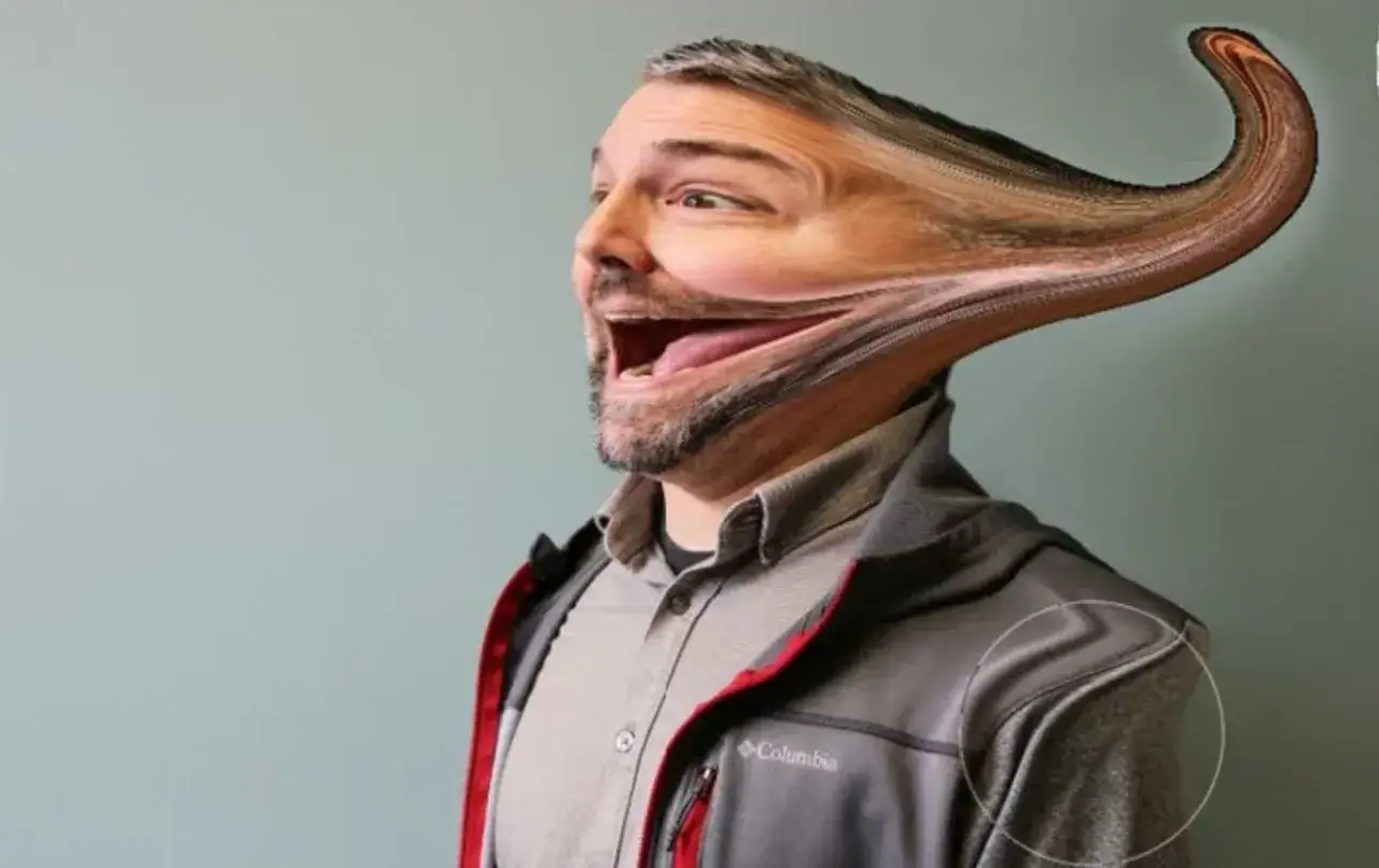 Un homme souriant, son visage étiré par l'outil fluidité Photoshop, créant un effet comique et surréaliste.