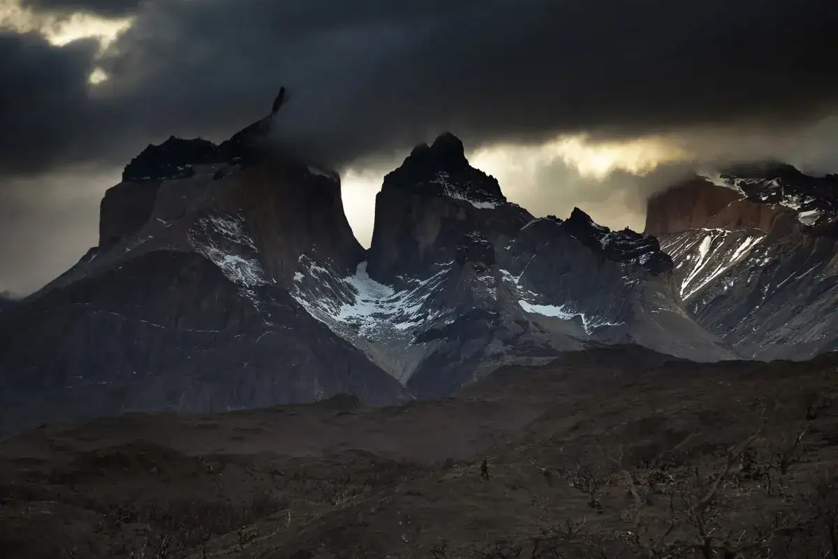 Un homme solitaire, Mathieu Le Lay, marche dans un paysage désolé sous des montagnes sombres et menaçantes.