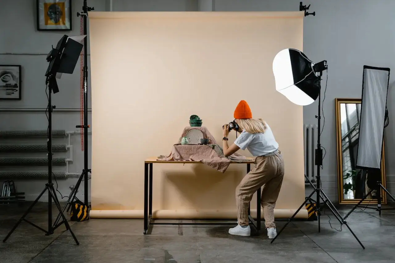 Photographe en action pour une photographie de produits, capturant des c&eacute;ramiques sur une table.