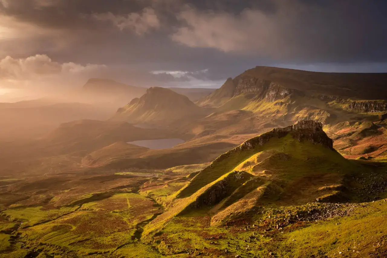 Paysage &eacute;cossais spectaculaire en grand angle, baign&eacute; par la lumi&egrave;re dor&eacute;e du soleil couchant. Des collines verdoyantes et des montagnes aux sommets escarp&eacute;s se d&eacute;ploient &agrave; perte de vue.