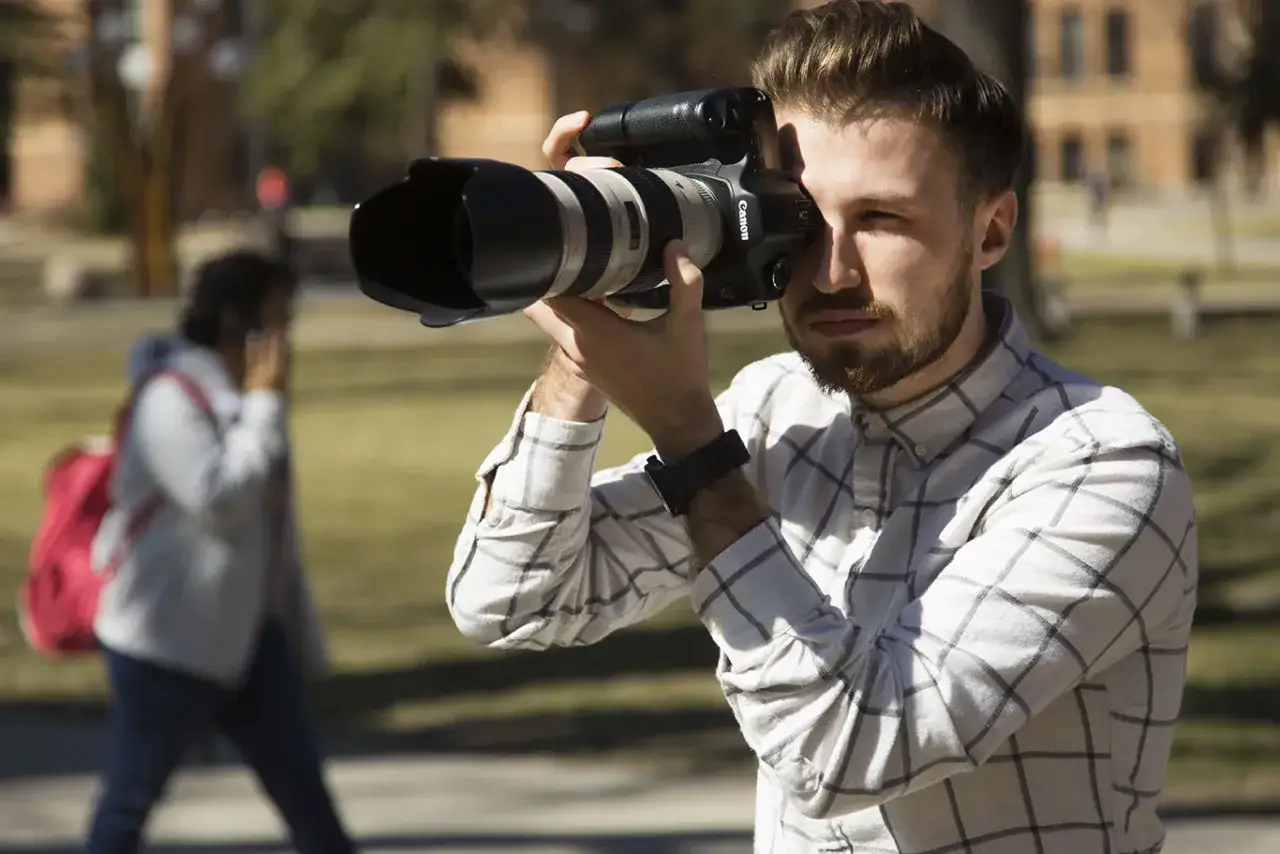 Un jeune homme, appareil photo en main, capture l'instant. Une scène de photojournalisme def. en plein air.